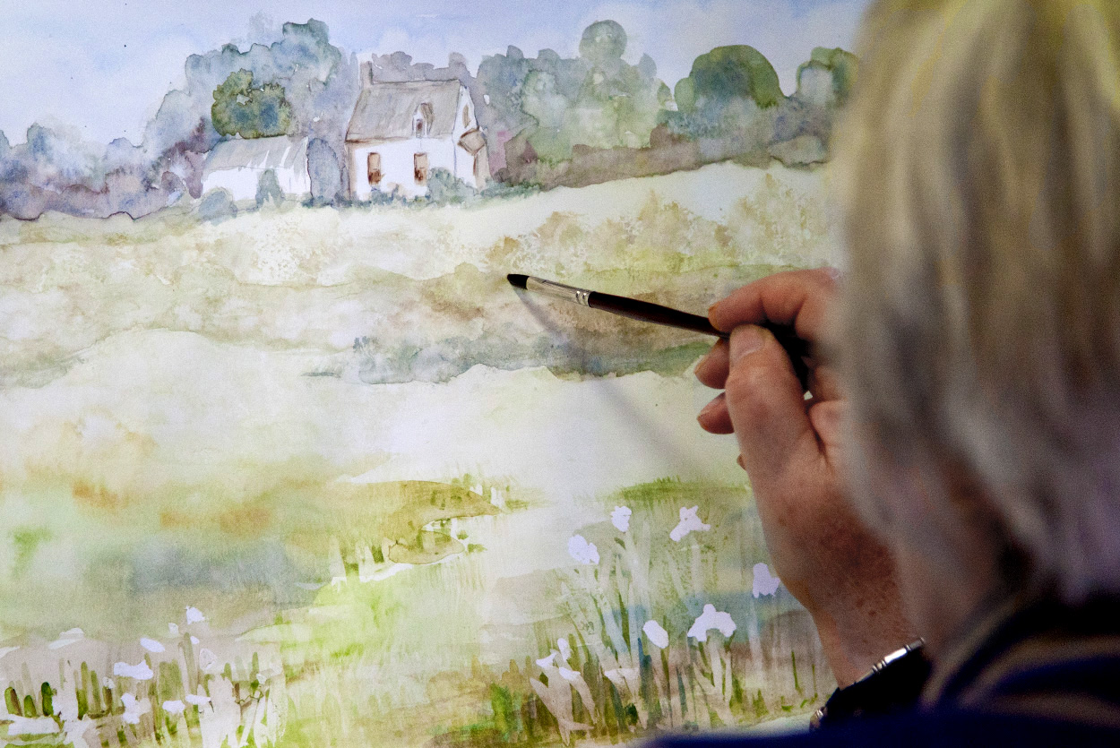 artist painting a landscape with a cottage